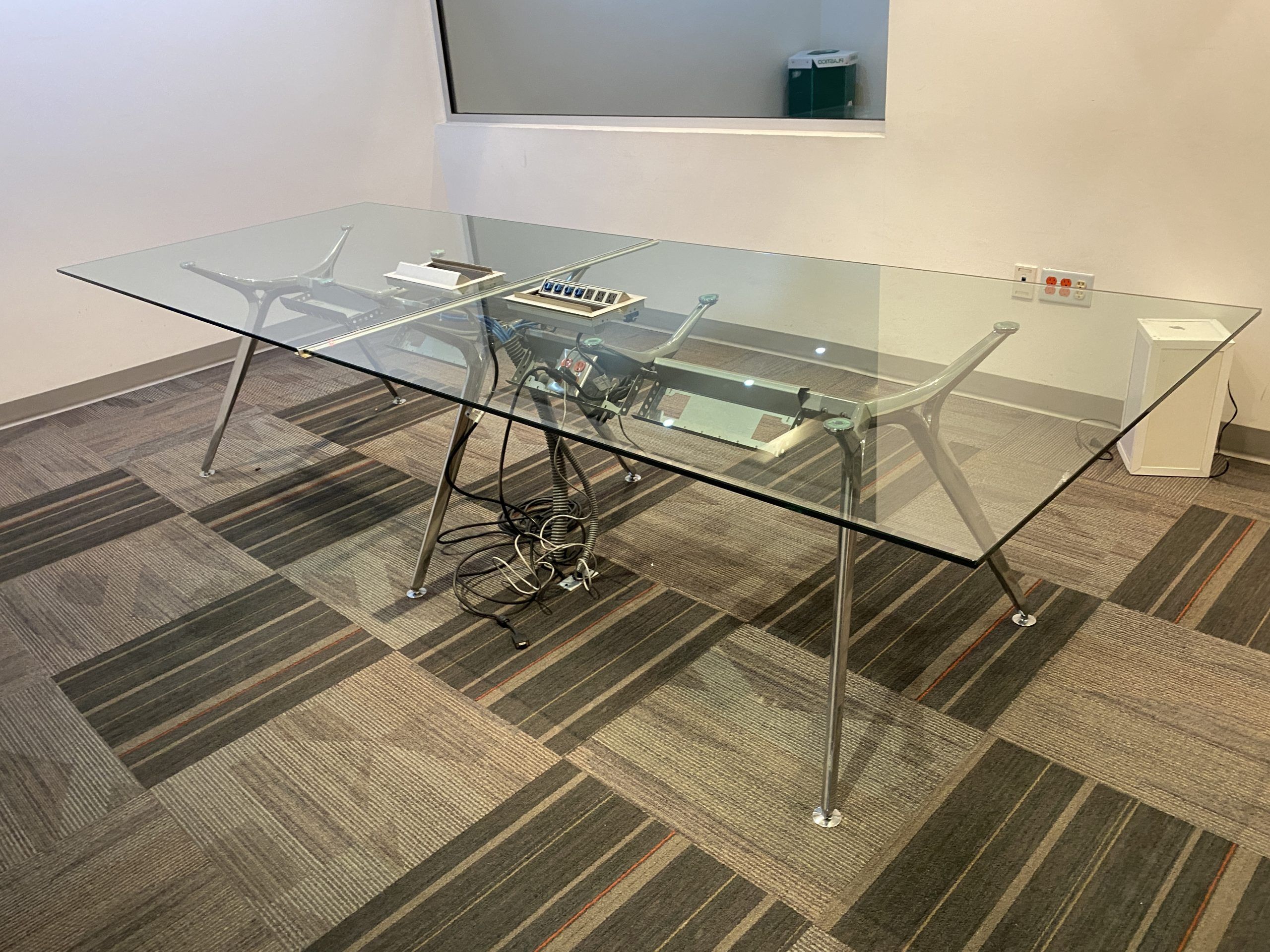 Lote 092 - Mesa de sala de juntas con base metálica y cubierta de vidrio en 2 piezas con accesorio para conexiones