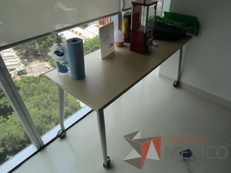 Lote 235 - Escritorio con patas metálicas con ruedas y cubierta color madera con orificios para cable